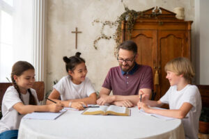 A group of children and an adult gather around a table with notebooks and a large book, engaged in a discussion.