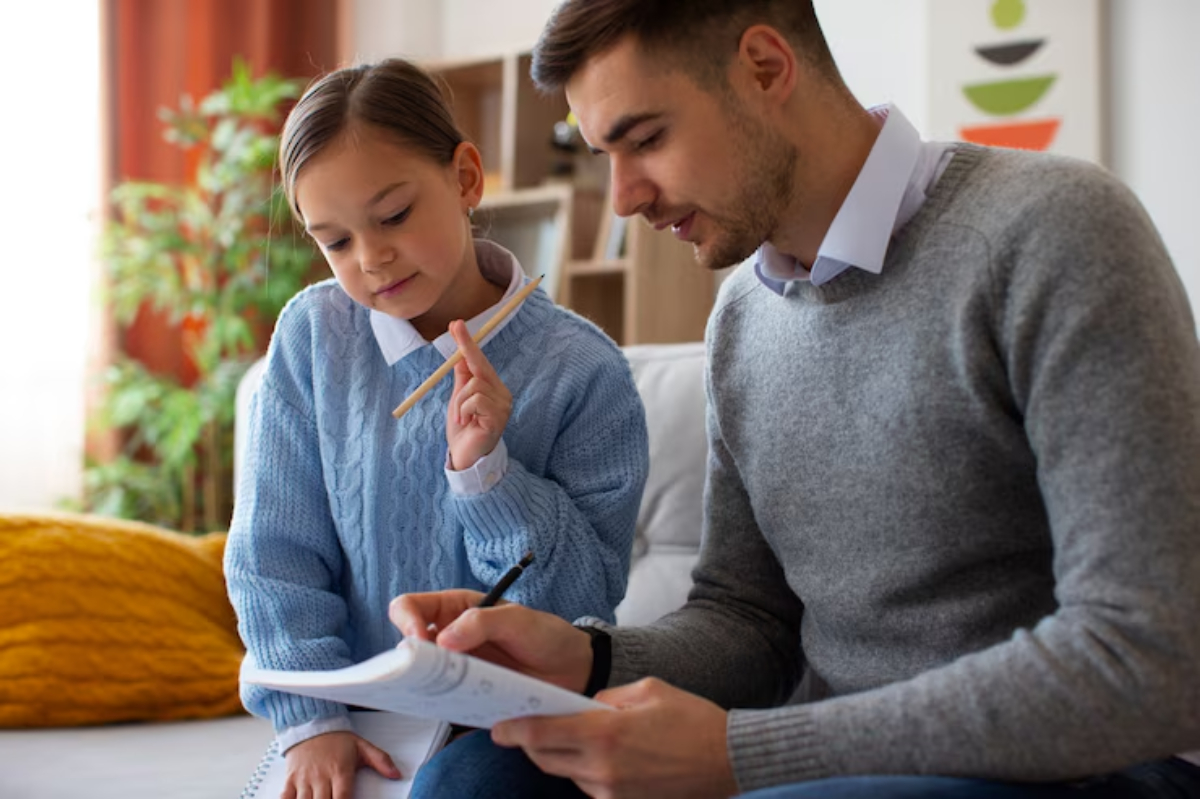 A child and adult are engaged in a discussion while studying on a couch, surrounded by natural light and indoor plants.