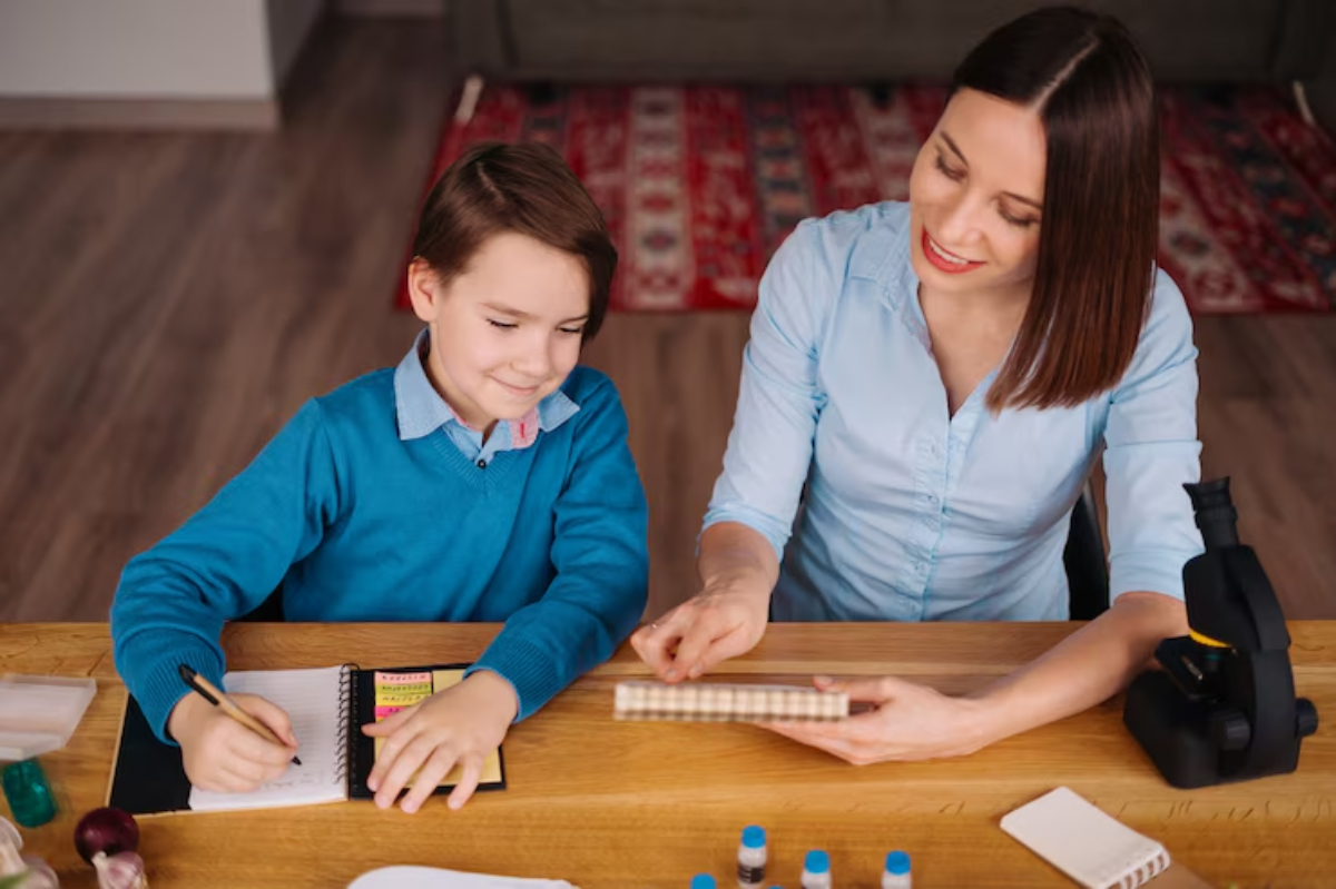 A woman and a child engage in a learning activity at a wooden table, surrounded by school supplies and a microscope.