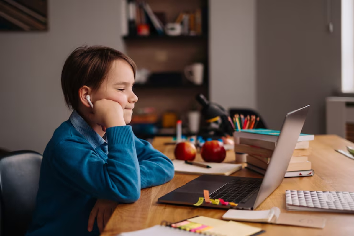 A child sits at a wooden desk, wearing earbuds, surrounded by books, apples, stationery, and a laptop, in a cozy study environment.
