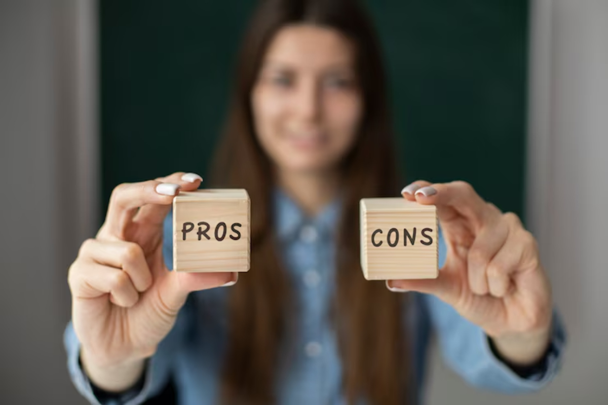 A person holds wooden blocks labeled PROS and CONS, weighing options against a blurred background.