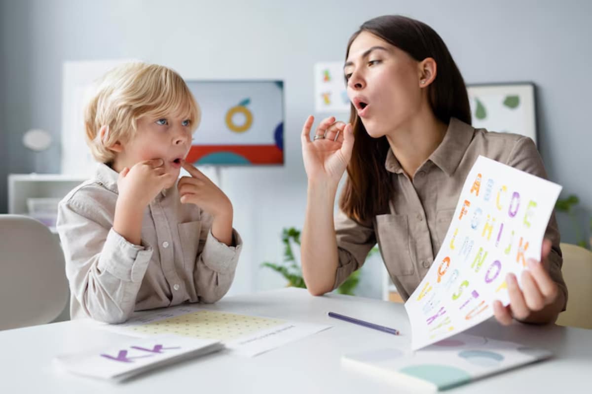 A child and an adult engage in a learning activity, reviewing colorful alphabet cards on a tidy table in a modern classroom setting.