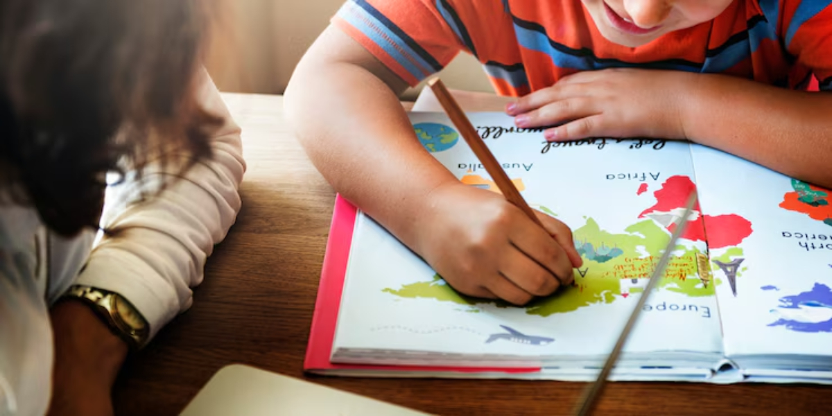 A child in a striped shirt happily colors a map in a colorful book, while an adult supports and observes nearby.