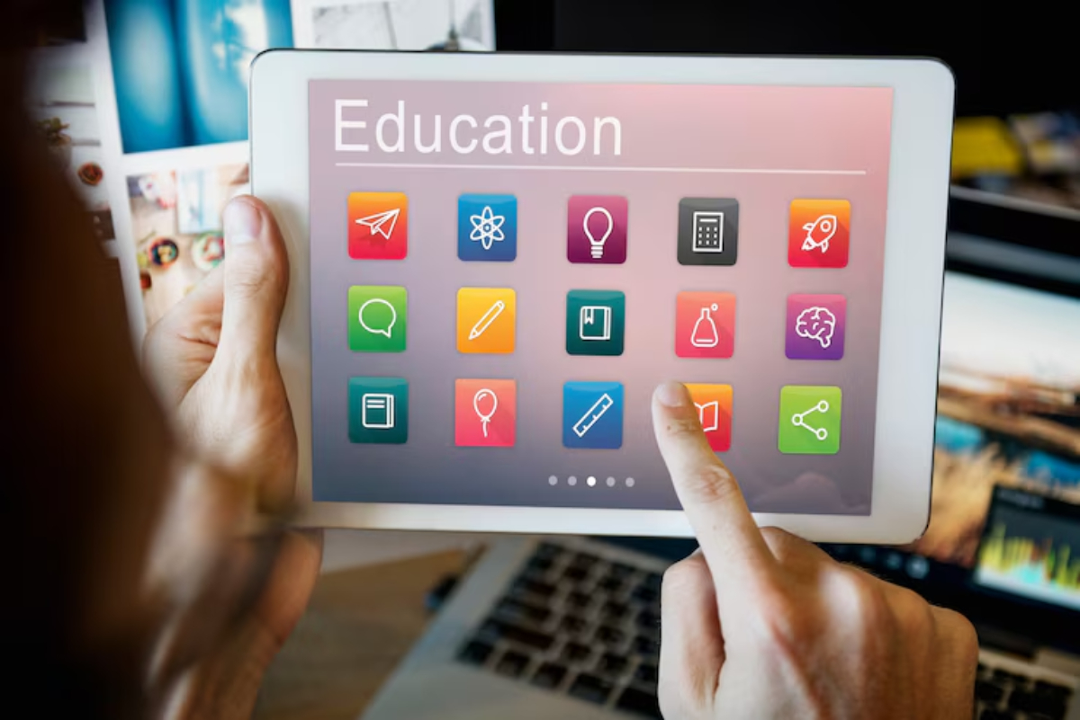 A person interacts with a tablet displaying a colorful education app interface featuring various icons representing different subjects.